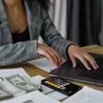 A businesswoman working on finance management with cash and calculator on desk.